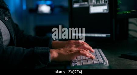 Close Up On Hands Of Female Computer Hacker Sitting In Front Of Screens Breaching Cyber Security Stock Photo