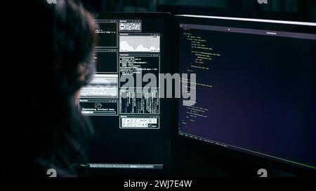 Over The Shoulder Shot Of Female Computer Hacker In Front Of Screens Breaching Cyber Security Stock Photo