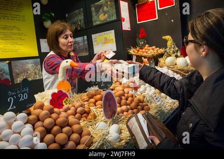 The owner of an egg stall selling half dozen of them to a customer in the old Abaceria Central Market of Barcelona Stock Photo