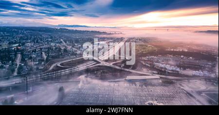 Aerial view of cityscape at sunset, featuring freeway bridges immersed in fog Stock Photo