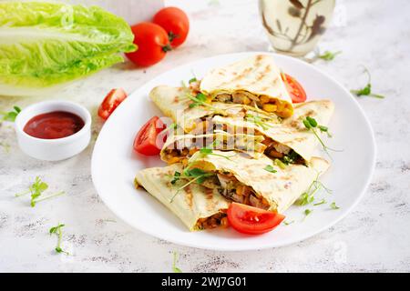 Mexican Quesadilla wrap with chicken, corn and sweet pepper on white plate. Stock Photo