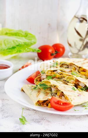Mexican Quesadilla wrap with chicken, corn and sweet pepper on white plate. Stock Photo