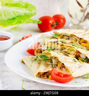Mexican Quesadilla wrap with chicken, corn and sweet pepper on white plate. Stock Photo