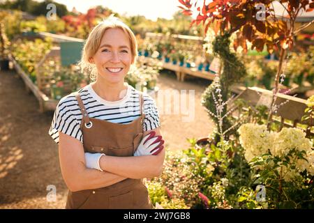 Portrait Of Smiling Woman Working Outdoors In Garden Centre Stock Photo