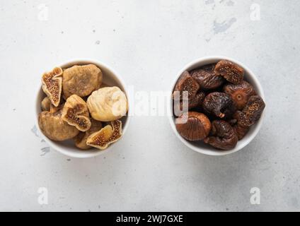 Two kitchen bowl plates with white and brown organic dried organic figs on light background. Stock Photo