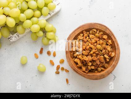 Green sweet dried raisins in wooden bowl on light background with ripe grapes. Stock Photo