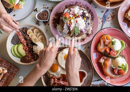 Breakfast is served with various dishes including eggs, bacon, pancakes and fruits on a colorful table Stock Photo