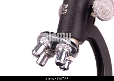 an old microscope stands isolated on a white background on a white surface with real shadows Stock Photo