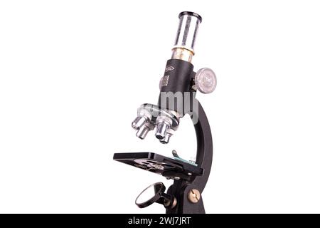 an old microscope stands isolated on a white background on a white surface with real shadows Stock Photo