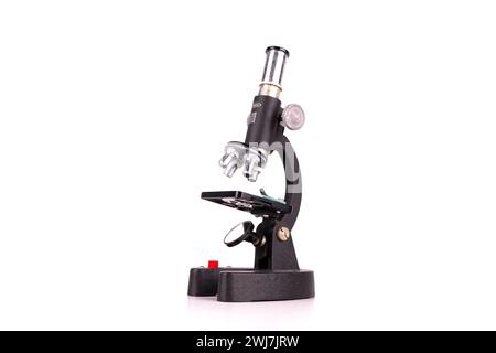 an old microscope stands isolated on a white background on a white surface with real shadows Stock Photo