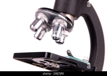 an old microscope stands isolated on a white background on a white surface with real shadows Stock Photo