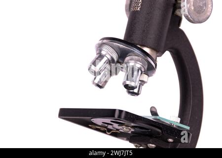an old microscope stands isolated on a white background on a white surface with real shadows Stock Photo