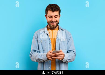 Happy young man browsing an app on his smartphone, studio Stock Photo
