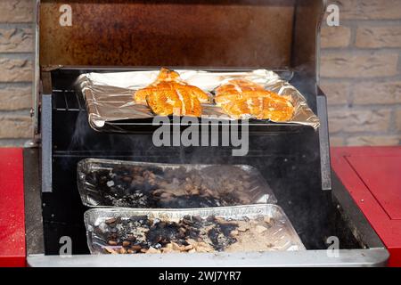 Close-up of an outdoor kitchen with an open flap showing fresh wild salmon steaks to be smoked with apple wood and oak wood Stock Photo