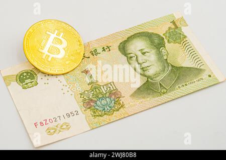 China money bill yuan with bitcoin. Golden-plated Bitcoin on Chinese yuan note. Renminbi. Chinese Yuan money and cryptocurrency Bitcoin close-up. Digi Stock Photo
