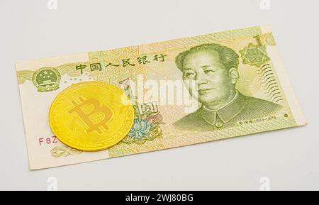 China money bill yuan with bitcoin. Golden-plated Bitcoin on Chinese yuan note. Renminbi. Chinese Yuan money and cryptocurrency Bitcoin close-up. Digi Stock Photo