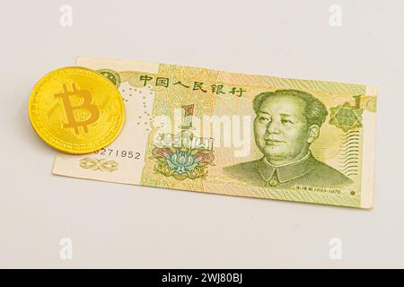 China money bill yuan with bitcoin. Golden-plated Bitcoin on Chinese yuan note. Renminbi. Chinese Yuan money and cryptocurrency Bitcoin close-up. Digi Stock Photo