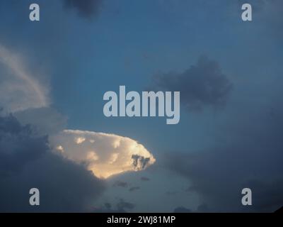 Sun shining through clouds over beach with red umbrella Stock Photo