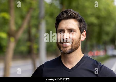 Close-up photo of a happy and satisfied young athletic man standing outside and looking confidently to the side. Stock Photo