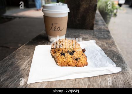 Homemade scone and tea in a paper cup outside on a bench Stock Photo