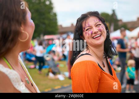Two Female Friends Wearing Glitter Having Fun At Summer Music Festival Doing Cheers With Drinks Stock Photo