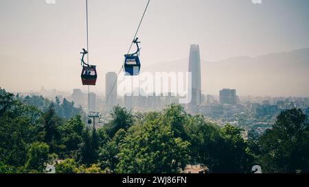 The gondolas of the Teleferico cable car in Santiago de Chile on San Cristobal Mountain disappear in the smog of the city between the skyscrapers. Stock Photo