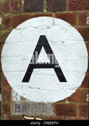 Letter A in black painted on a white circle on a brick wall Stock Photo