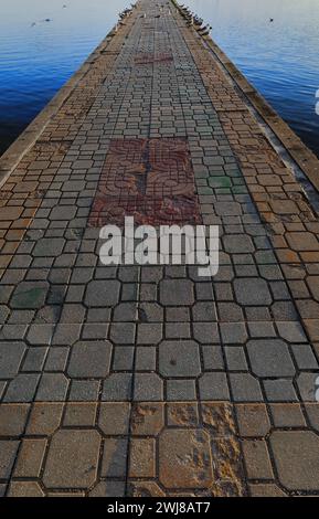335 Long pier with gulls perched on it jutting from Kej Makedonija promenade into the lake reaching an old swimming court ruins. Ohrid-North Macedonia Stock Photo