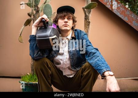 Young stylish male hipster wear in retro 90s old-fashioned style hold audio tape cassette recorder player. Stock Photo