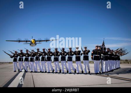 Marines of the Silent Drill Platoon, Marine Barracks Washington, execute their drill sequence during the Blue Angels  “Fat Albert” C-130J Super Hercules fly-over at Marine Corps Air Station, Yuma, Ariz., Feb. 13, 2024. The performance was the start of this year’s Battle Color Detachment Tour. (U.S. Marine Corps photo by Lance Cpl. Chloe N. McAfee) Stock Photo