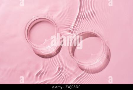 Two Petri dishes on rippled pink background. Abstract nature background of product presentation. Flat lay cosmetic mockup, space for copy . Stock Photo
