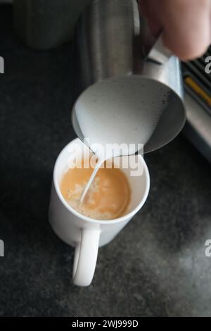 Pouring steamed milk for a latte, making coffee, barista Stock Photo
