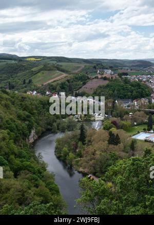 Bad Munster, Germany - May 12, 2021: Nahe River flowing between hills with trees with Rheingrafenstein Castle on a hill in the background on a spring Stock Photo
