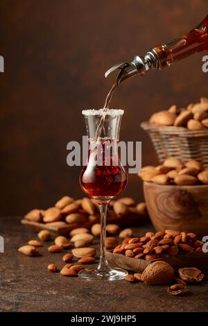 Strong alcoholic Italian liqueur Amaretto with almonds nuts on a wintage table. Stock Photo