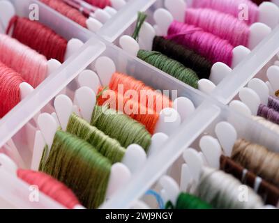 A close-up shot of a plastic sorting box full of bobbins with different colour embroidery threads. Stock Photo