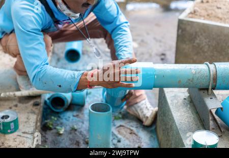 Worker fixing the connecting tube of water tank in construction site. Stock Photo