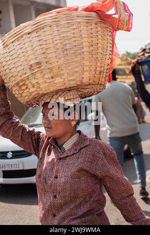 Woman carrying a basket on her head, Goa India. Indian woman with big basket on her head. In India, that's a popular way to bring heavy things. Street Stock Photo