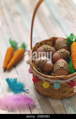 Flat lay composition of colourful painted easter eggs in a hay basket on wooden table. Happy Easter celebration Stock Photo