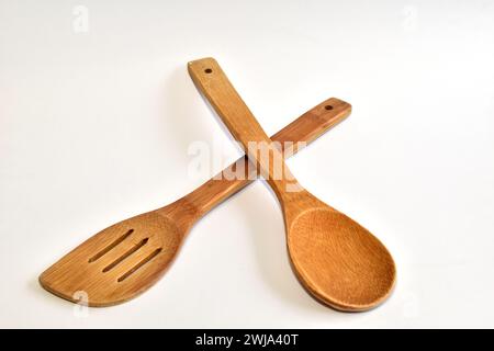 Kitchen tool. On a white background lies a wooden spoon with a long handle and a spatula. Stock Photo