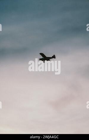 A single-engine airplane silhouetted against the dusky sky over Miami, Florida, with pastel hues on the horizon. Stock Photo