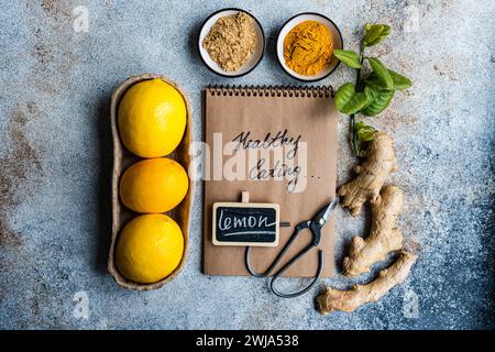 Fresh lemons, ginger, and spices displayed around a notepad with Healthy eating written on it Stock Photo