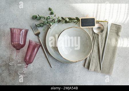 Stylish table setting with vintage-inspired glassware, cutlery, and plates, accented by natural greenery Stock Photo