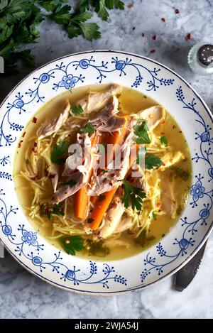 Warm bowl of chicken noodle soup with carrots and parsley, perfect for comfort food Stock Photo