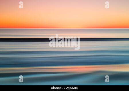 Soft focus on a tranquil Mediterranean seascape at sunset with smooth lines and a gradient of orange to blue Stock Photo
