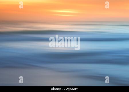 Blurred motion of waves with a warm sunset glow over the Mediterranean, creating a painting-like seascape Stock Photo