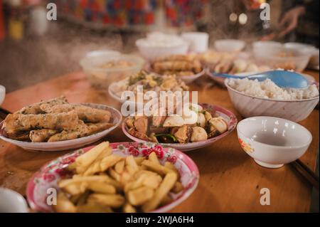 From above of various tasty Vietnamese dishes in ceramic plates and bowls placed on wooden table against blurred background Stock Photo