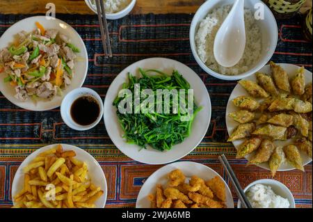 From above of delicious fried potato soup sauce salad rice spring rolls served on checkered tablecloth in restaurant Stock Photo