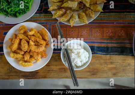 Top view of plates with fries, spring rolls vegetable and rice with chopsticks served on wooden table in Vietnam restaurant Stock Photo
