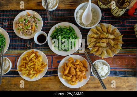 From above of delicious fried potato soup sauce salad rice spring rolls served on checkered tablecloth in restaurant Stock Photo