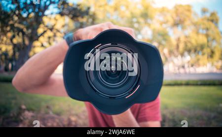 A photographer's camera lens in sharp focus with a bokeh effect creating a blurred background Stock Photo